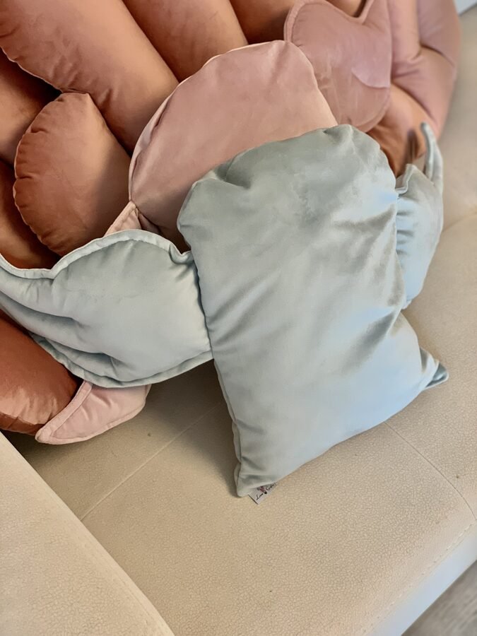 3. Close-up of grey velvet cushion with wing design on pink velvet background