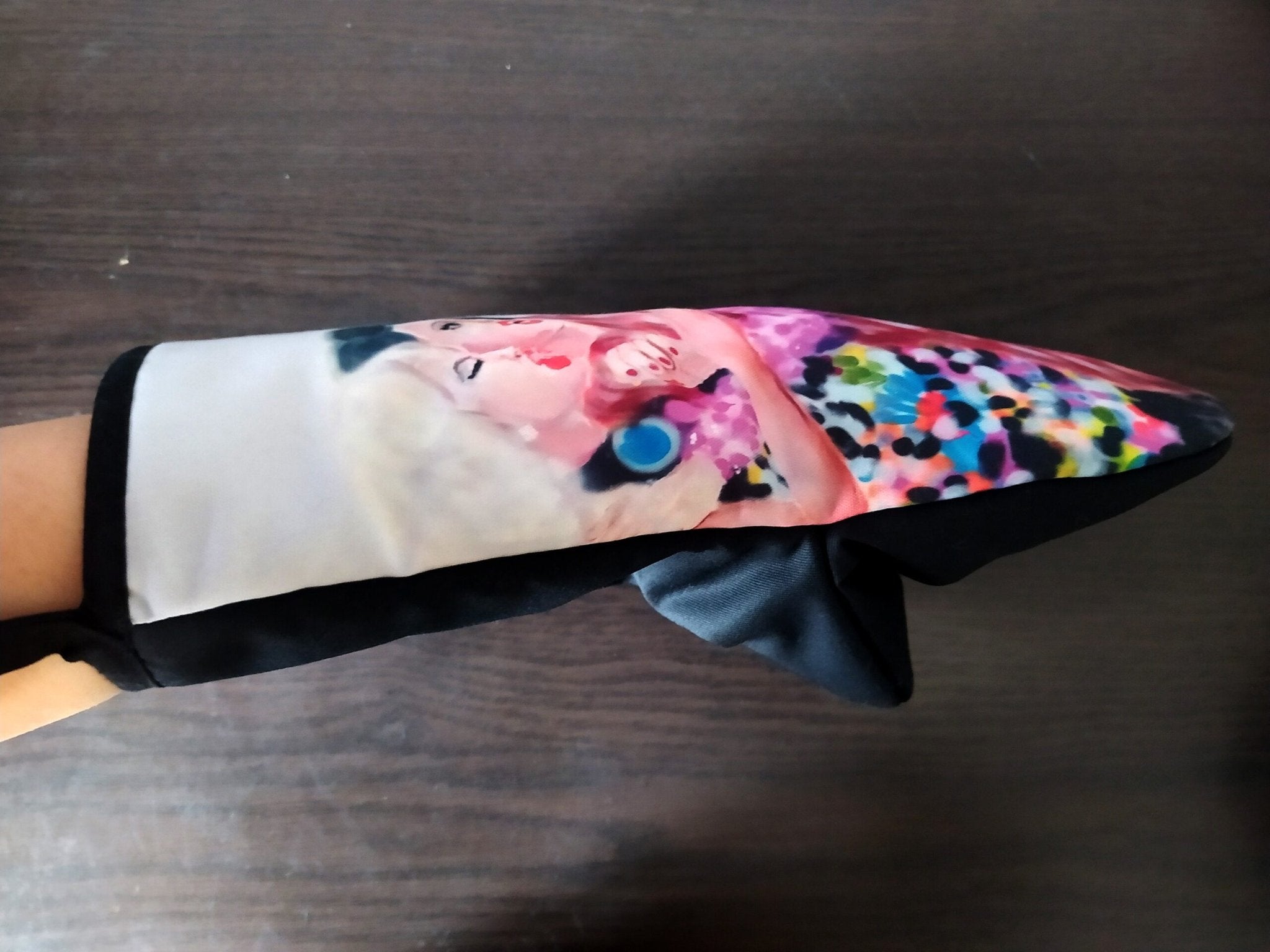 3. Close-up of Katrin Valgemäe oven glove worn on hand, showing detailed pop art design with women