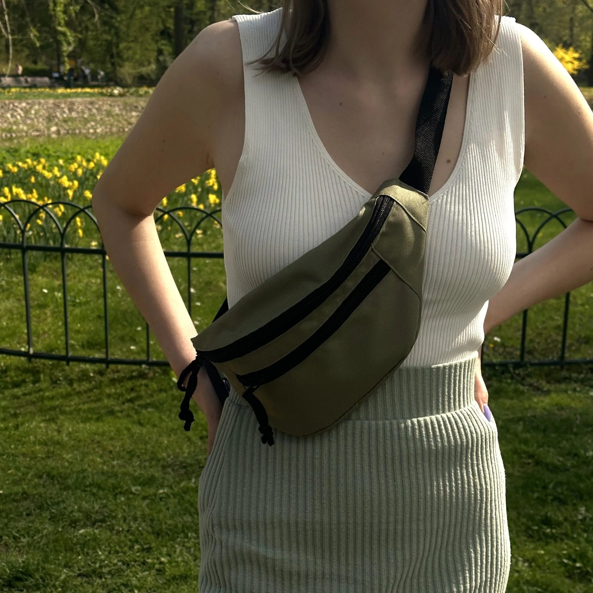 1. Women's Drinbags Classic Waist Bag in moss green worn crossbody in a park setting