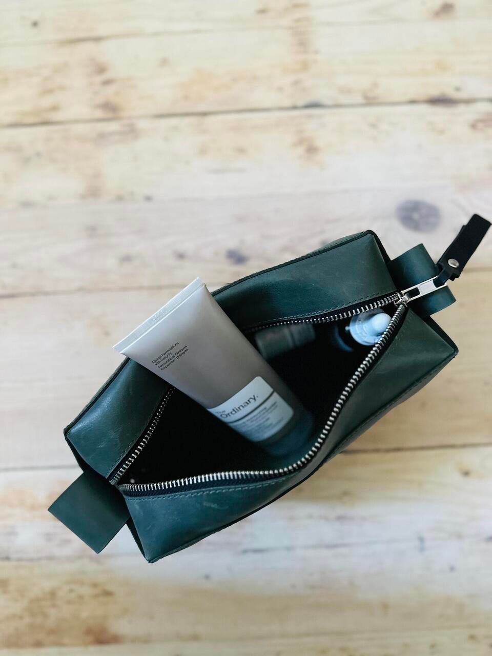 5. Interior view of eleriinseim leather cosmetic bag in Forest color with beauty products