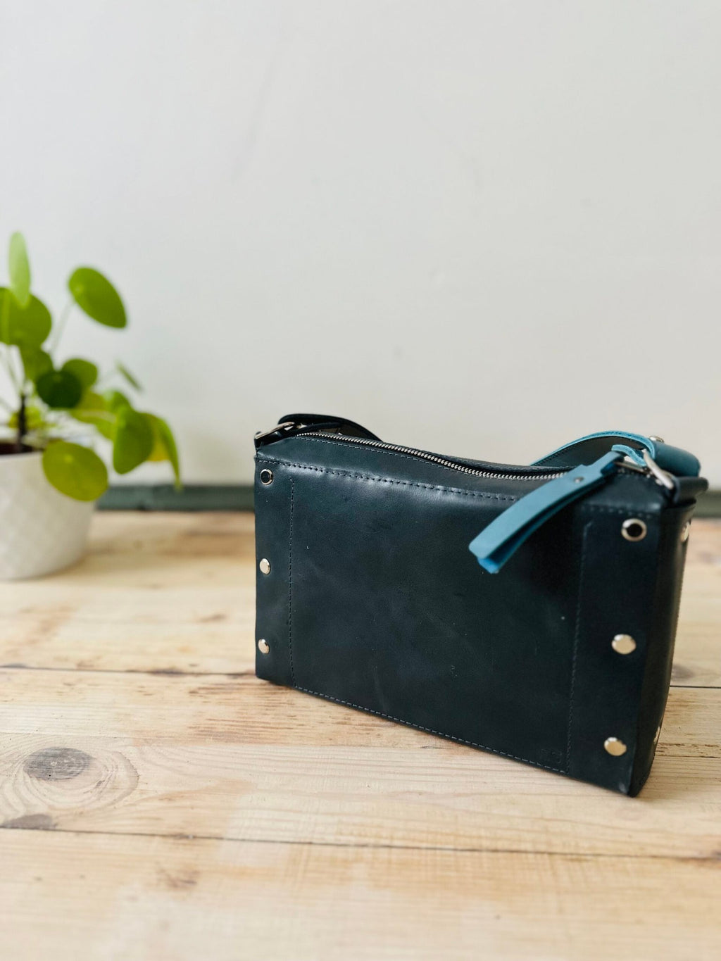9. Back view of eleriinseim TOURIST crossbody leather bag in Atlantic blue, highlighting rivet details and sturdy construction