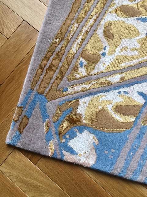 3. Close-up of Art Deco Diagonal Pink Rug corner showing intricate gold and blue pattern on wooden floor