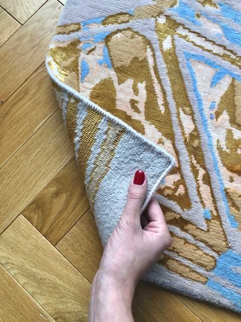 3. Detail of Art Deco Diagonal Pink Rug with hand lifting corner to reveal texture and pattern