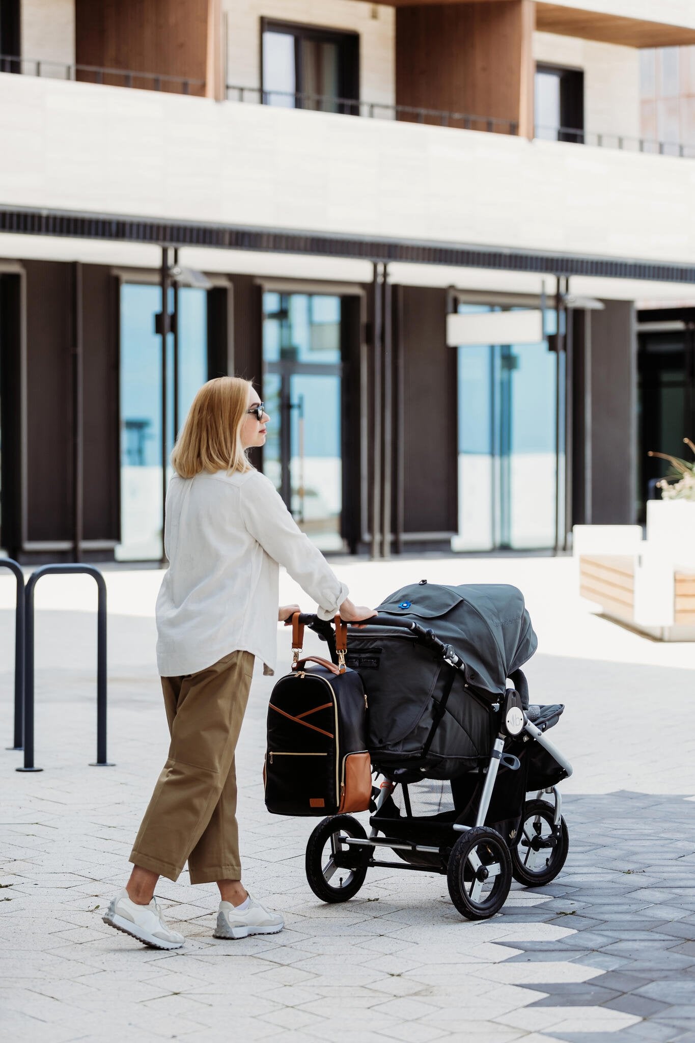 2. Woman pushing stroller with Ally Scandic Black Coffee diaper backpack attached
