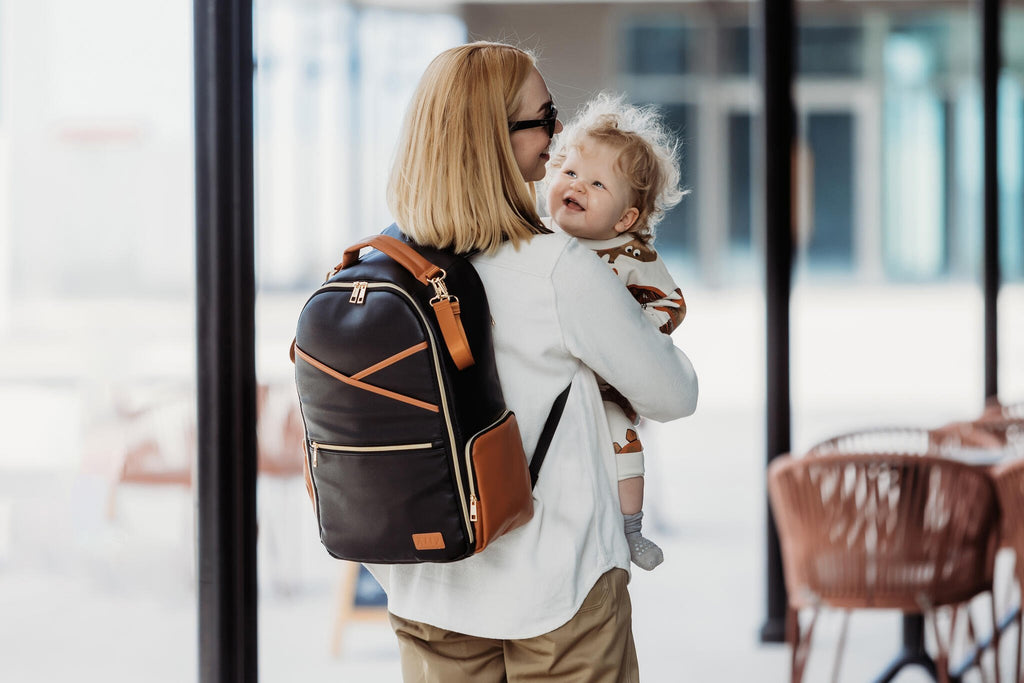 1. Woman carrying baby with Ally Scandic Black Coffee diaper backpack in lifestyle setting