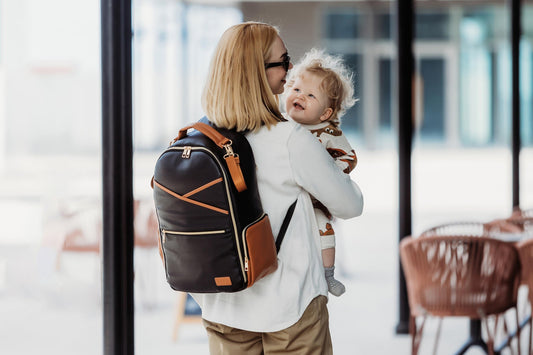 1. Woman carrying baby with Ally Scandic Black Coffee diaper backpack in lifestyle setting