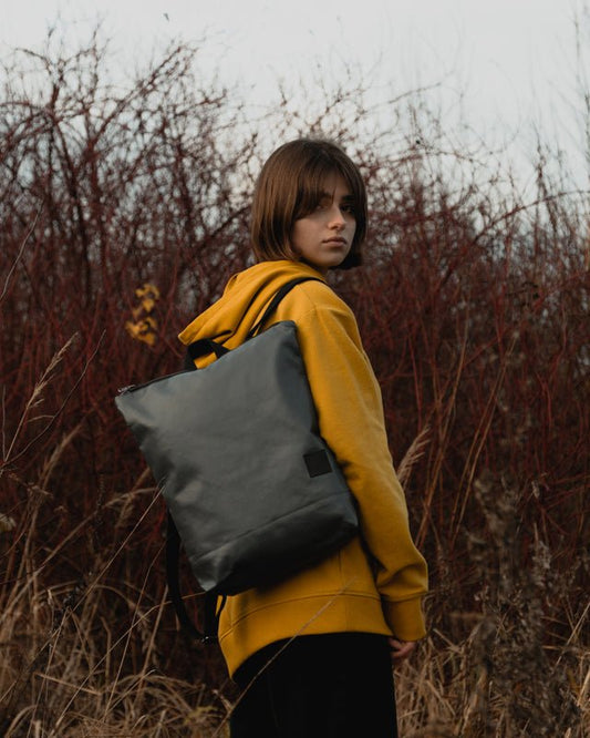 1. Woman wearing Muni faux leather grey backpack in outdoor setting