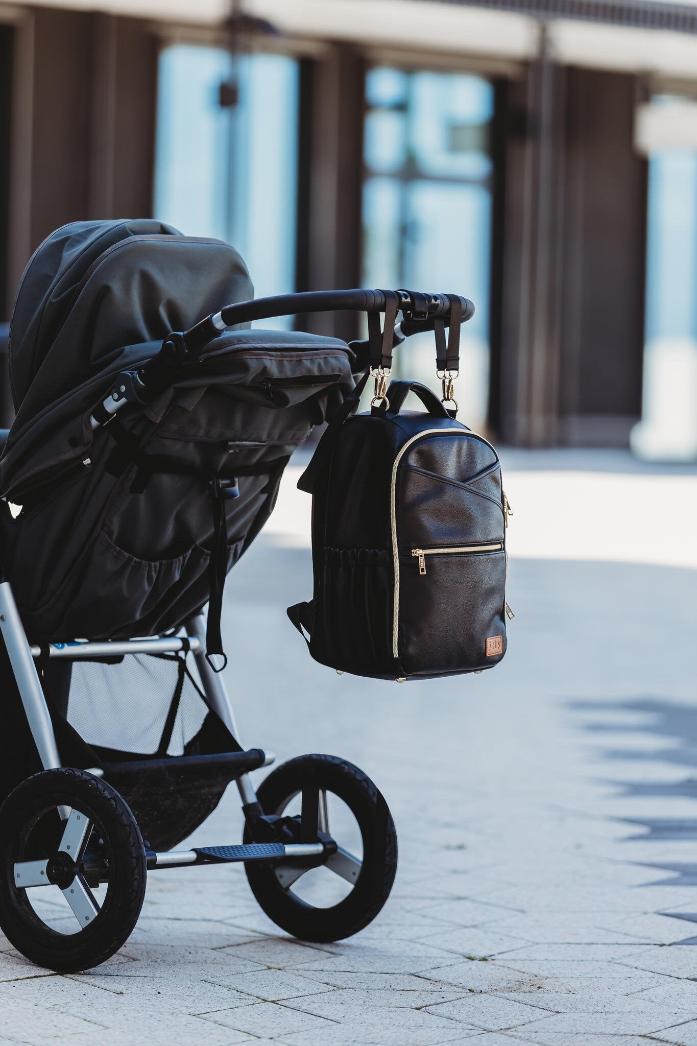 5. Ally Scandic Small Espresso Diaper Backpack attached to stroller outdoors