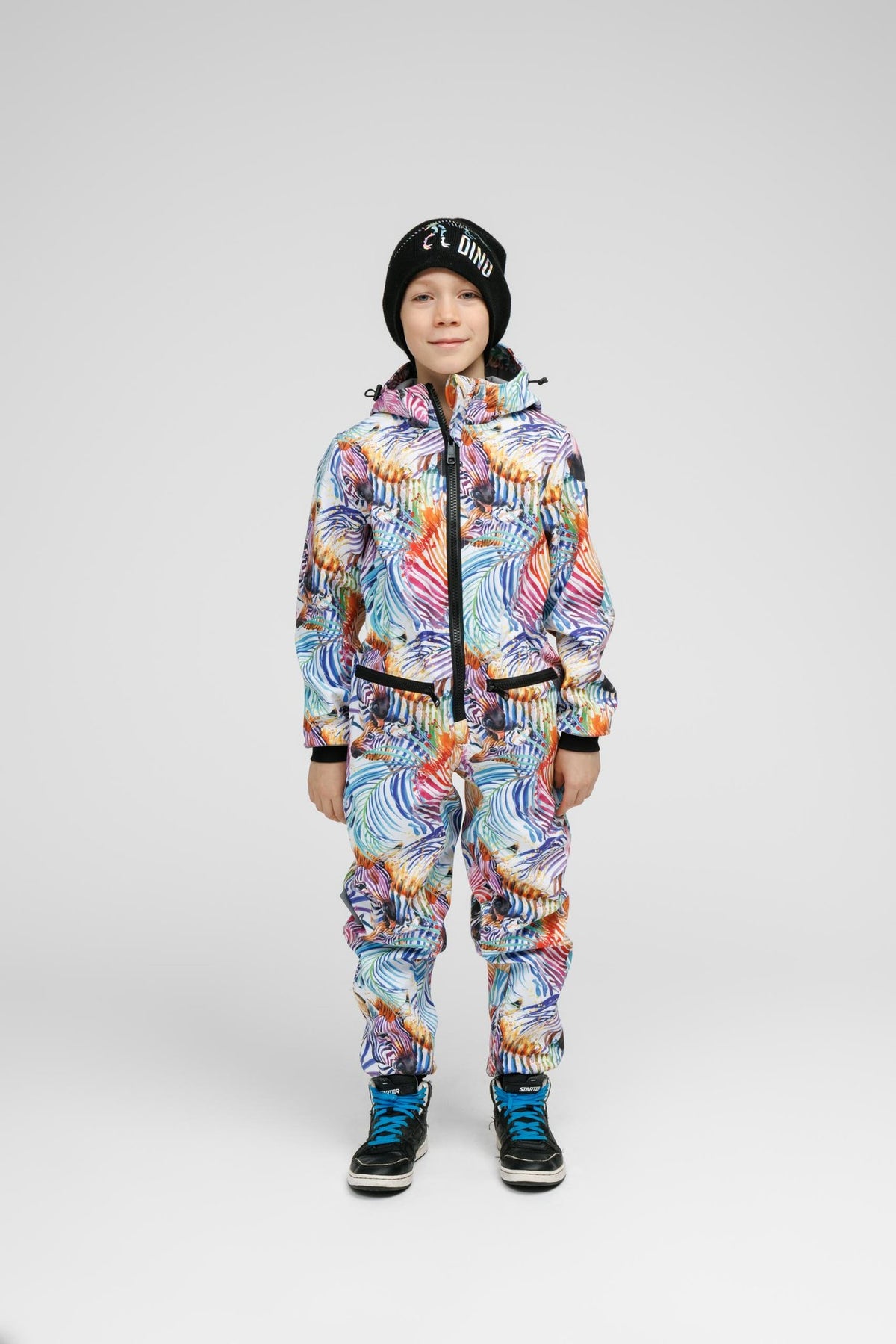 2. Child in Nuckö rainbow softshell onesie with black beanie, facing forward in studio