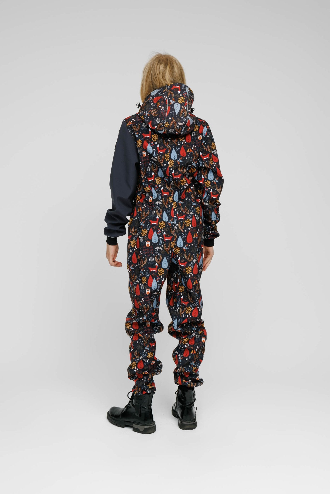 2. Child wearing Nuckö softshell onesie with forest print, shown from back in studio