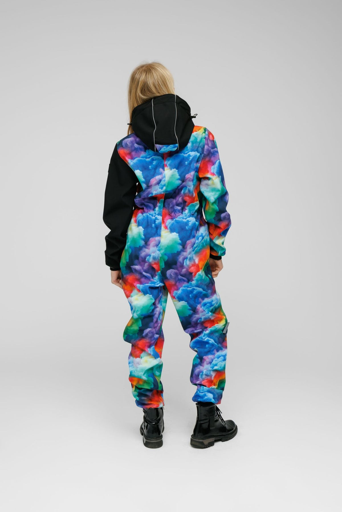 3. Back view of child in colorful softshell onesie with black hood and sleeves, showing reflective stripe detail