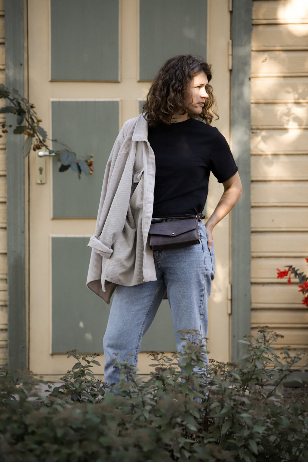 12. Woman wearing KOKUKA crossbody leather bag as a waist bag, styled with casual outfit outdoors