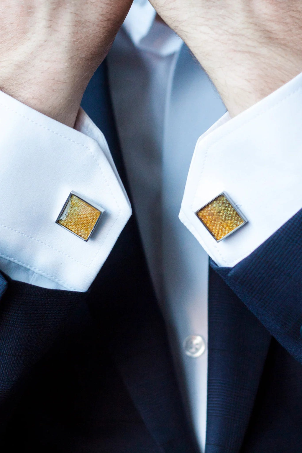 1. Man wearing white shirt with yellow leather square cufflinks by Eherüs, shown in close-up with hands near face