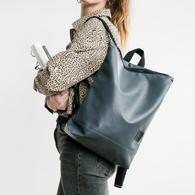 3. Woman with Muni faux leather grey backpack walking by ivy-covered wall
