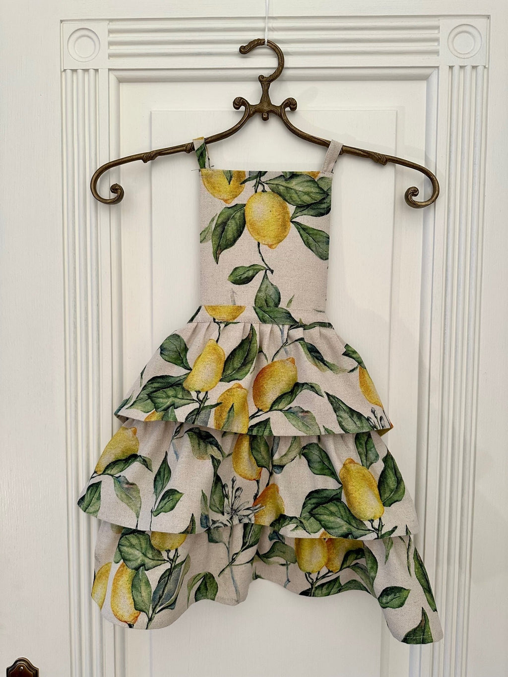 1. Ladies apron with ruffles in lemon print, displayed on hanger, Hortensias Home