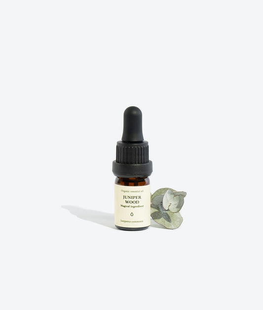 2. Smells Like Spells JUNIPER WOOD Essential Oil in 5 ml glass bottle with eucalyptus leaf, studio setting
