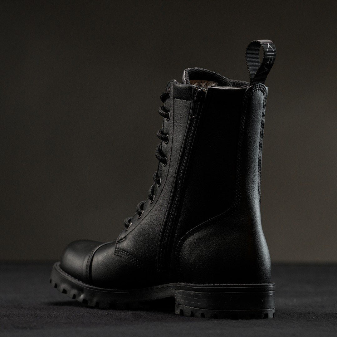 2. Side view of KIRA 6.0 black boots showing zipper and treaded sole, studio setting