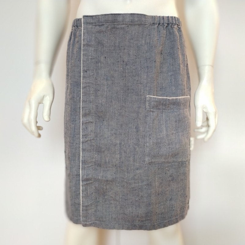 2. Front view of men's grayish blue linen sauna skirt with pocket and fishbone pattern on mannequin