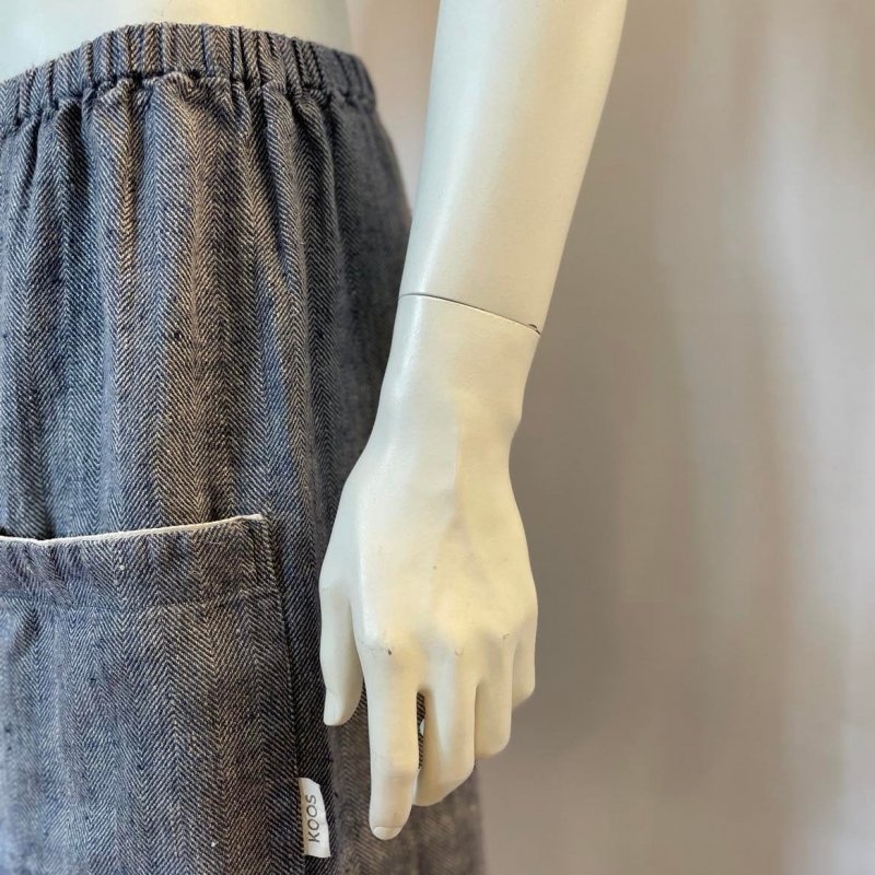 3. Close-up of grayish blue linen sauna skirt pocket and fishbone pattern with KOOSdisain tag