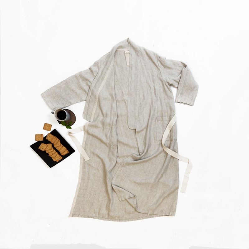 4. Flat lay of unisex grey linen bathrobe with cotton belt and pockets, accompanied by a cup and plate of biscuits on a white background