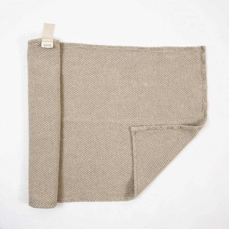 2. Beige linen sauna seat cover with fishbone pattern, folded to show texture and KOOSdisain label, on white background