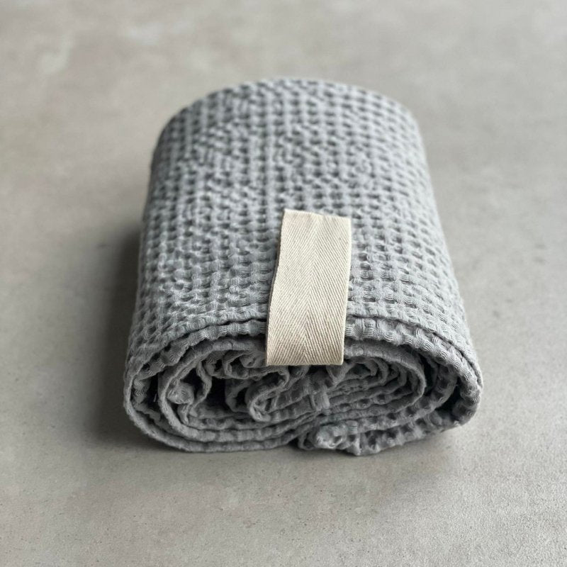 6. Rolled gray waffle fabric towel with white cotton hanger on concrete surface