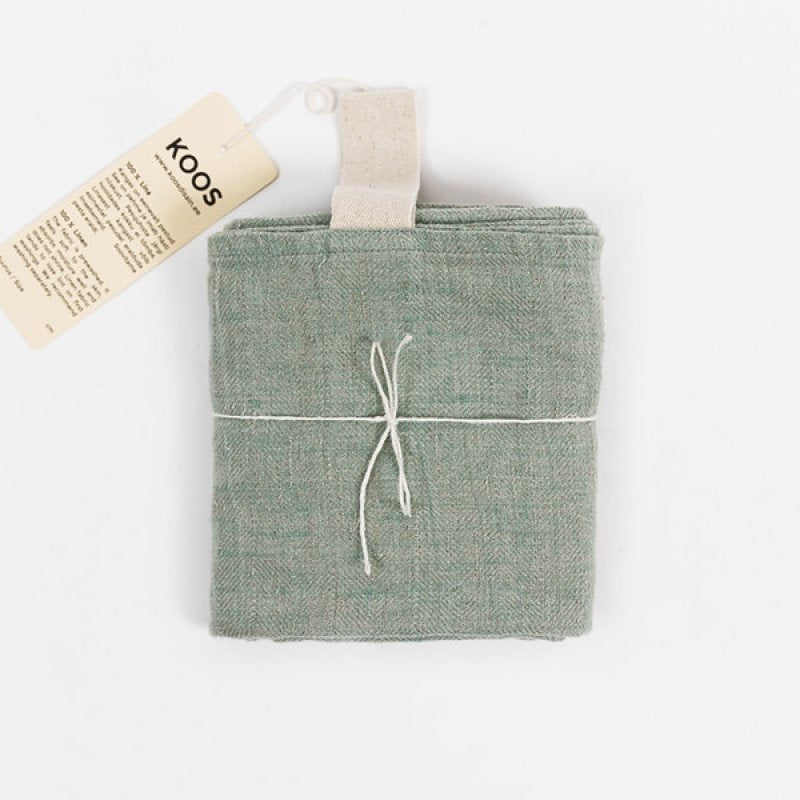 2. KOOSdisain big linen towel in mint green, folded and tied with string, featuring a natural white hanger and product tag on a white background