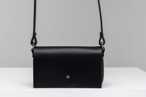 3. Studio shot of PYKOK KORA minibag in black leather with magnetic closure, displayed on white surface