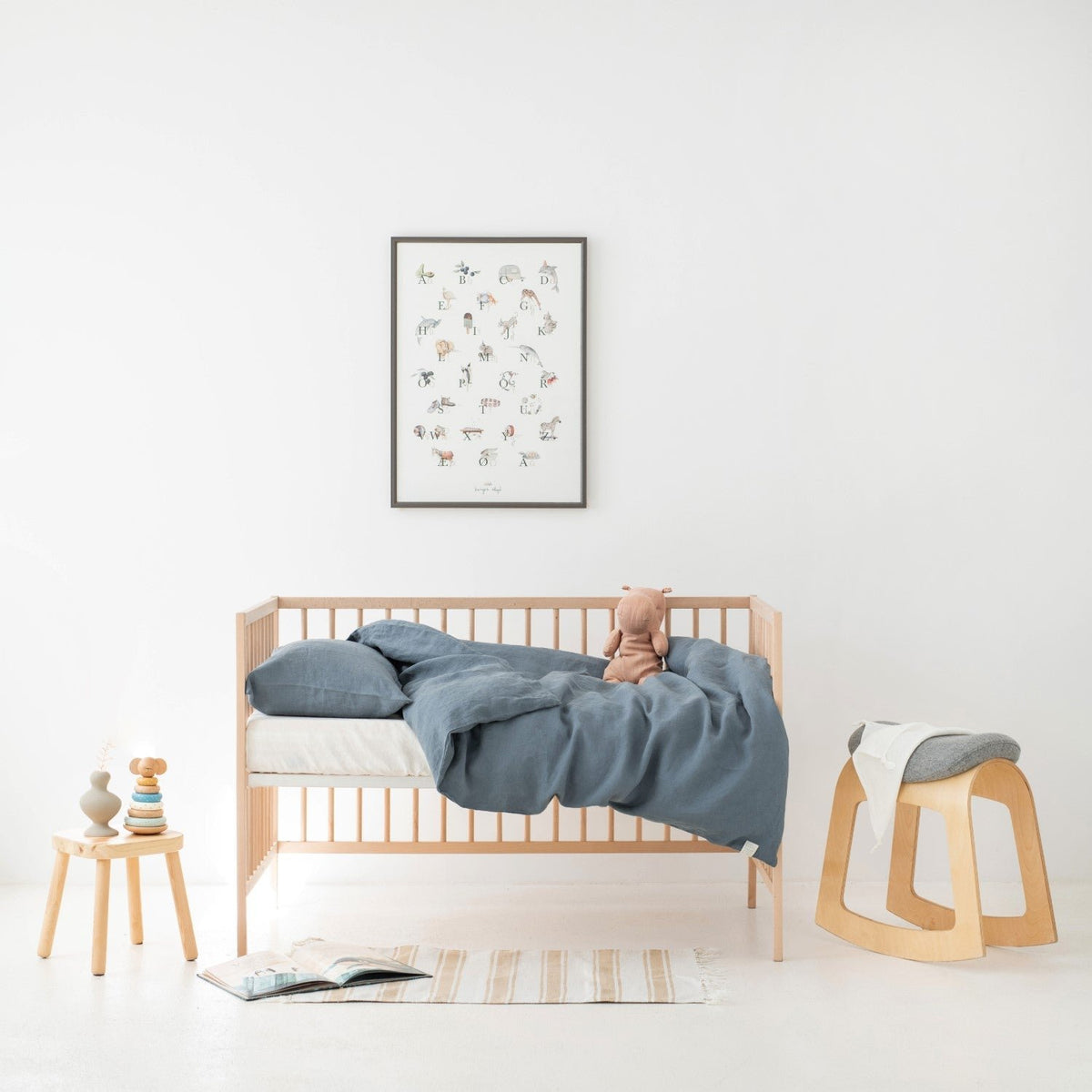 1. Kids' room with blue fog linen duvet cover set on a crib, featuring a plush toy and minimalist decor
