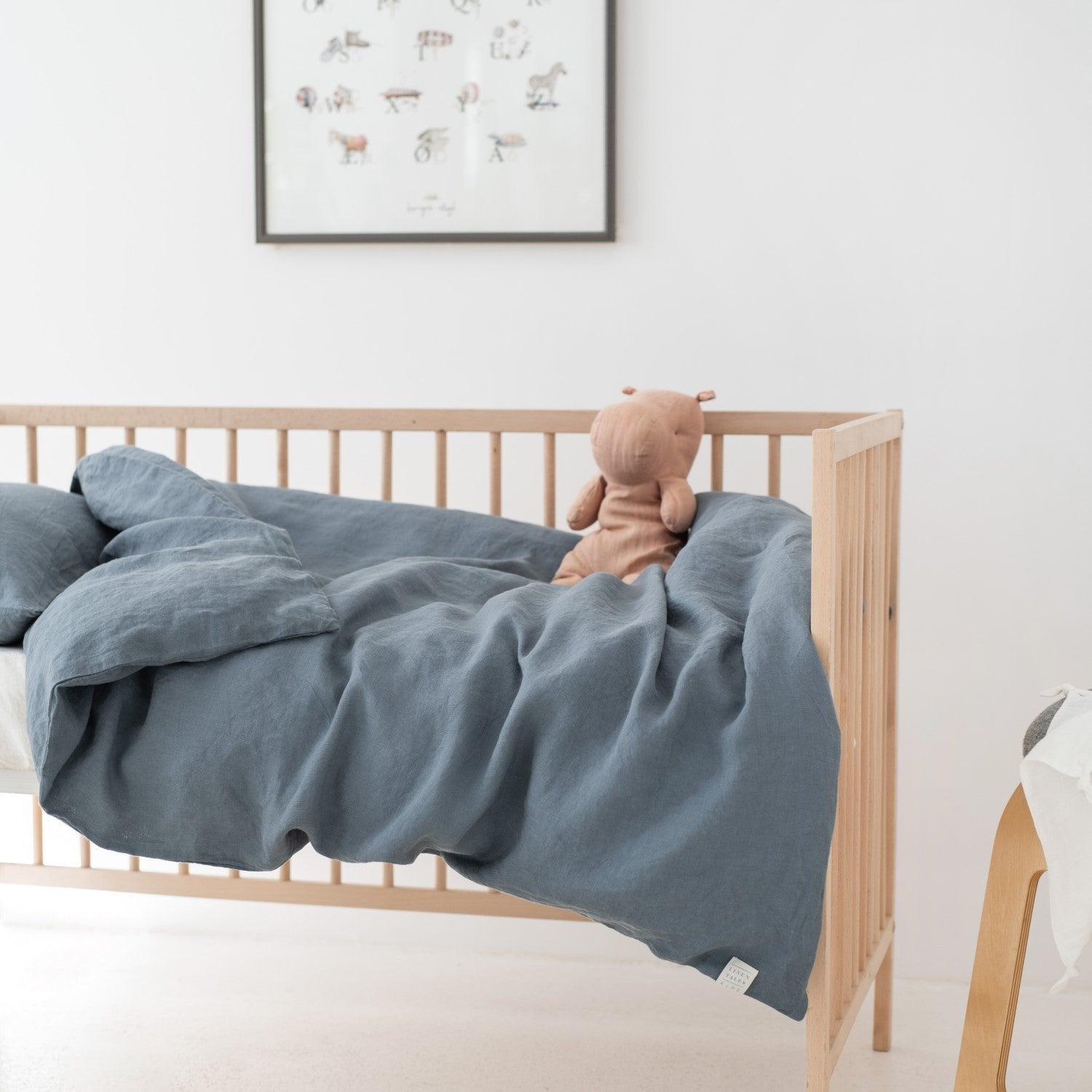 1. Blue fog linen duvet cover set on a kids' bed with a plush toy, in a minimalist nursery setting