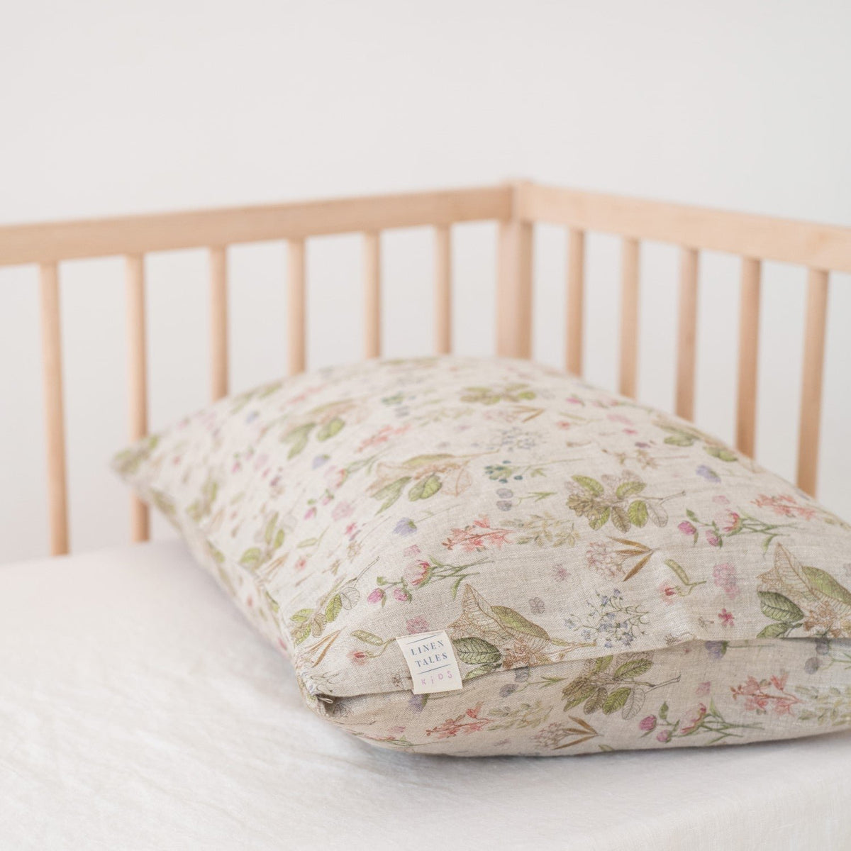 2. Botanical print linen pillowcase on kids' bed in wooden crib