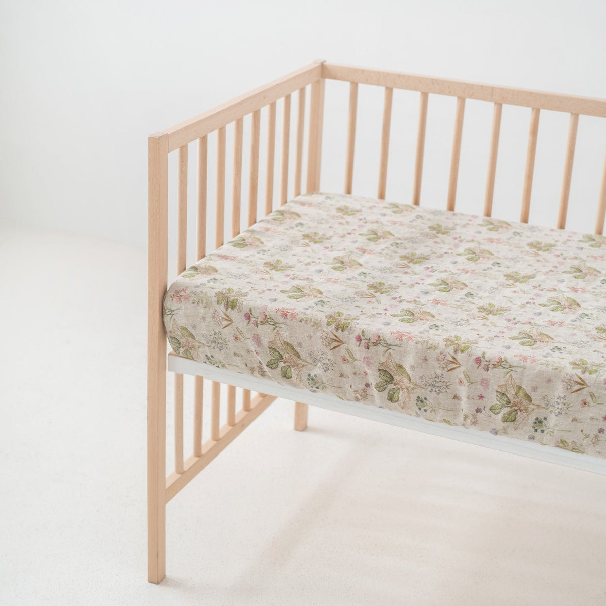 1. Kids linen fitted sheet with floral print on crib mattress in a light wooden crib