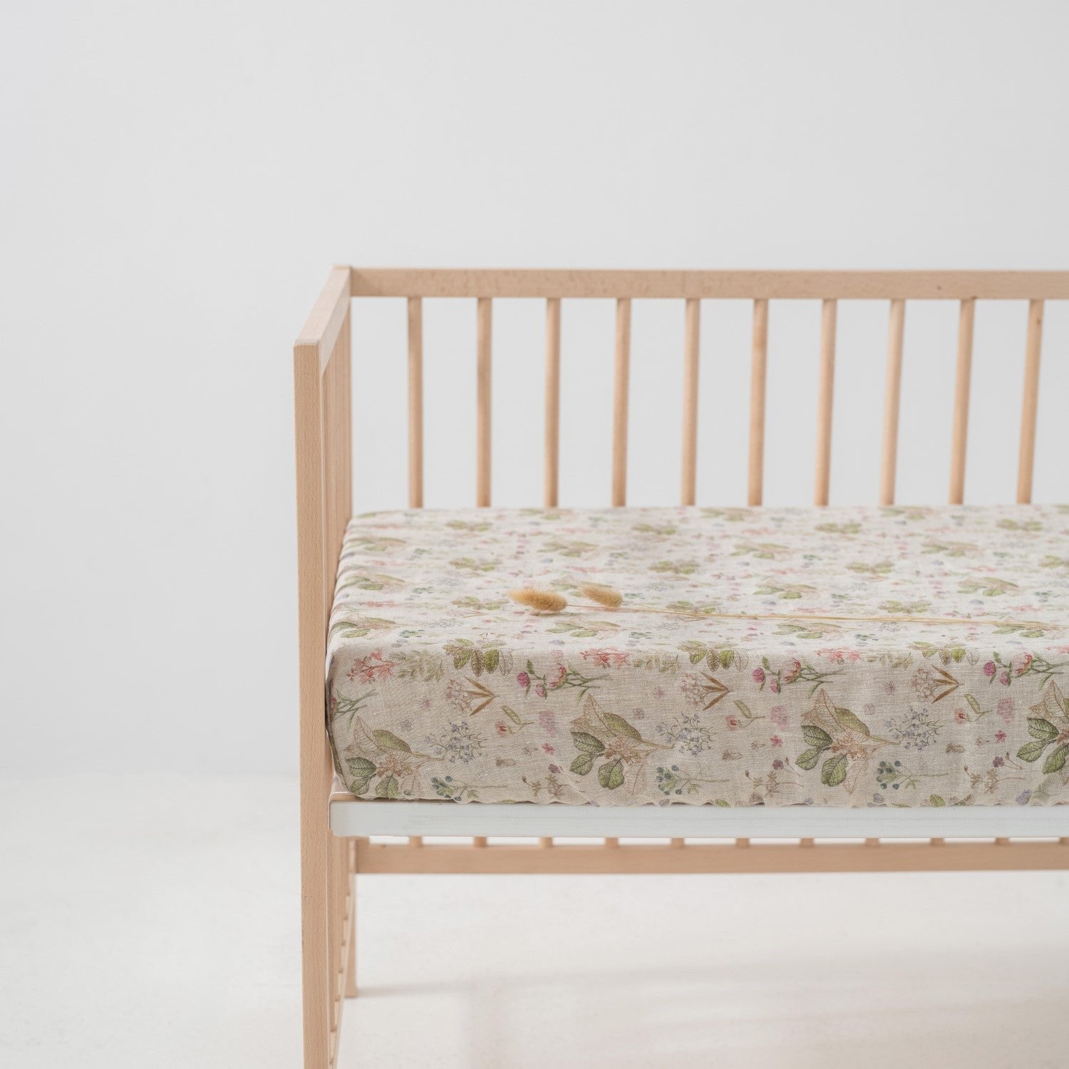 4. Kids sage linen fitted sheet with floral print on crib mattress in a minimalist nursery