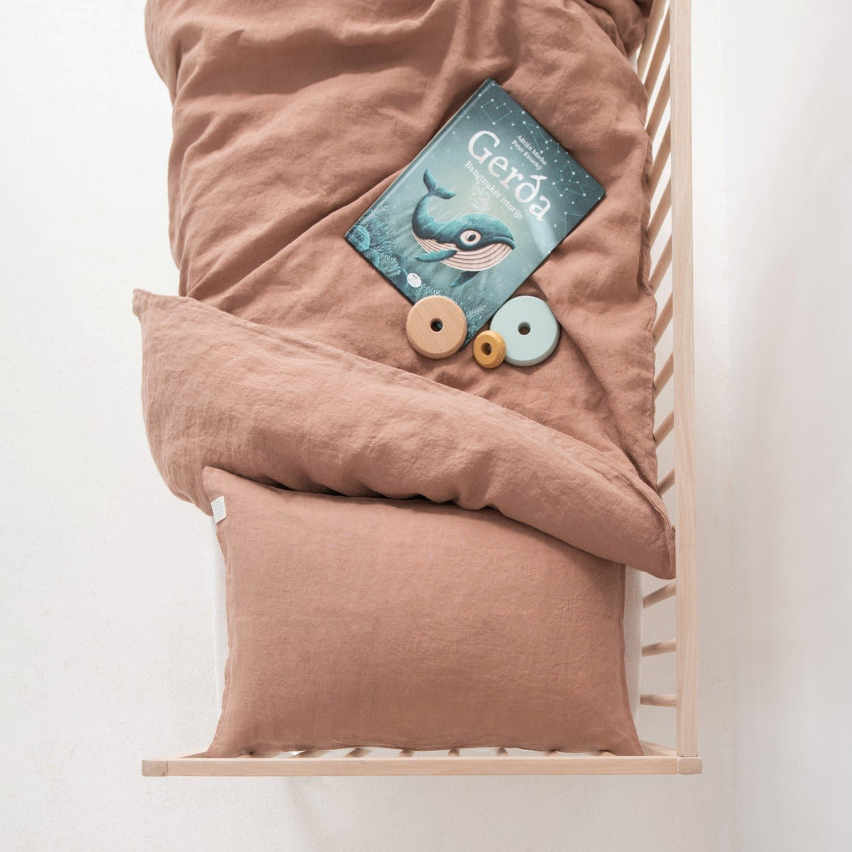 4. Top view of cafe creme linen duvet cover and pillowcase in crib with book and wooden toys