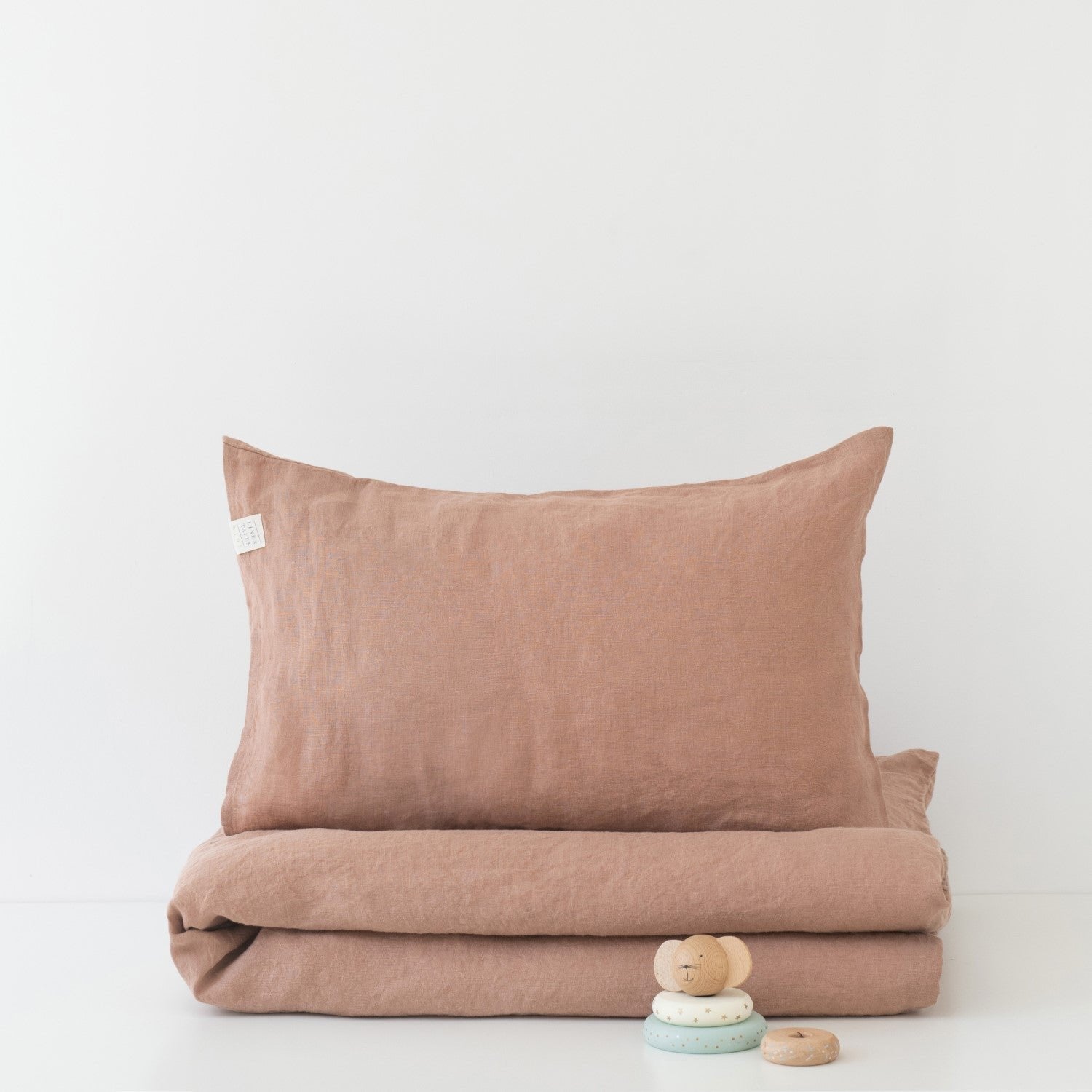 1. Cafe creme linen duvet cover set with pillowcase, folded neatly with small wooden toys on white background