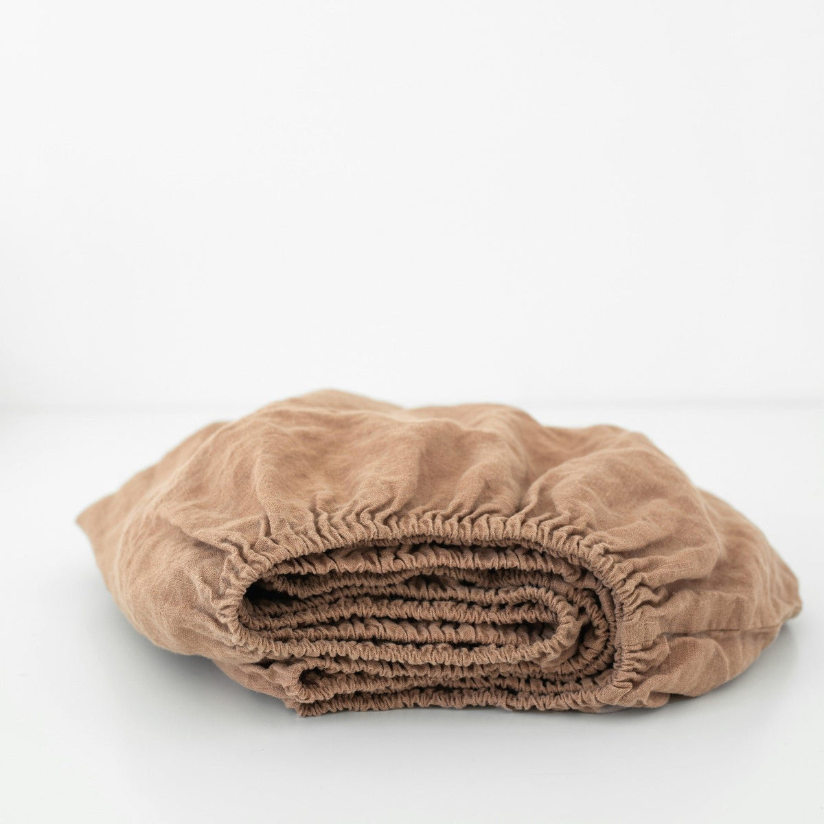 4. Folded cafe creme linen fitted sheet with visible elastic hem, highlighting the soft, durable fabric