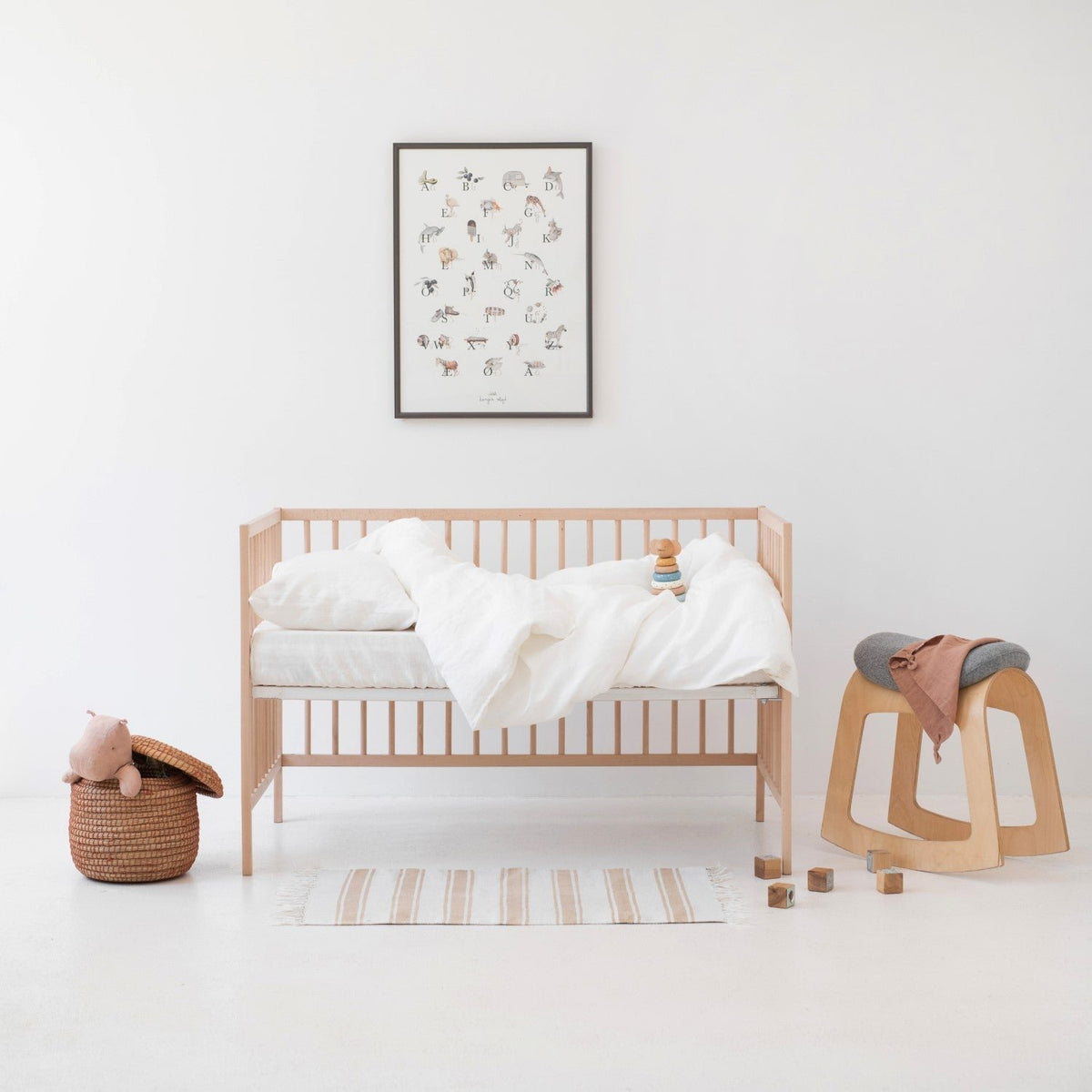 1. Kids' room with white linen duvet cover set on a wooden crib, surrounded by toys and decor
