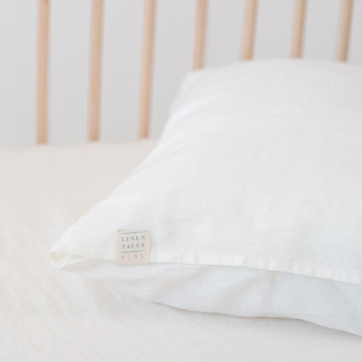 3. Close-up of white linen pillow with Linen Tales label on a crib
