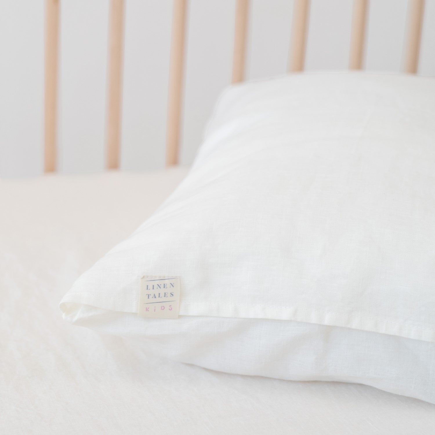 3. Close-up of white linen pillow with Linen Tales label on a crib
