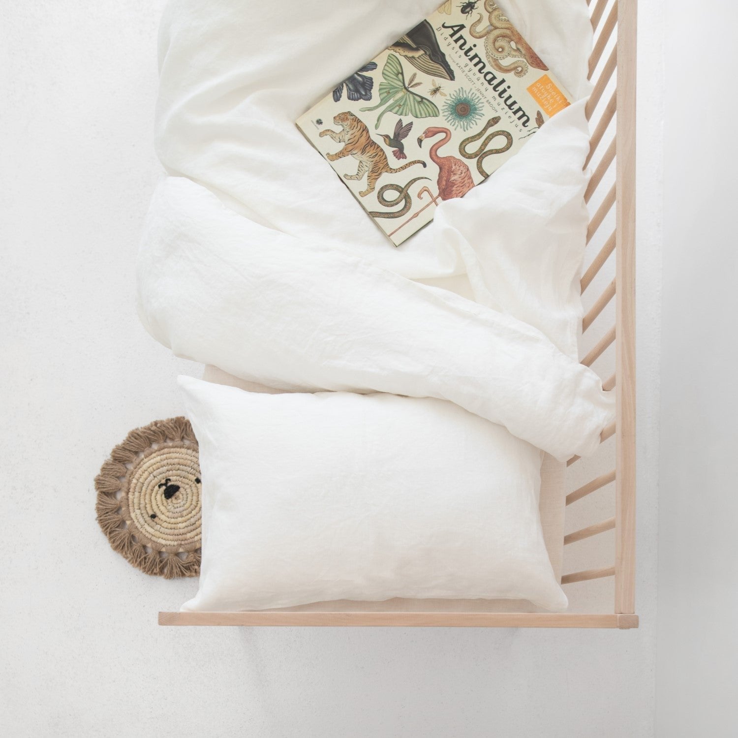 1. Top view of white linen duvet cover set on a crib with a children's book
