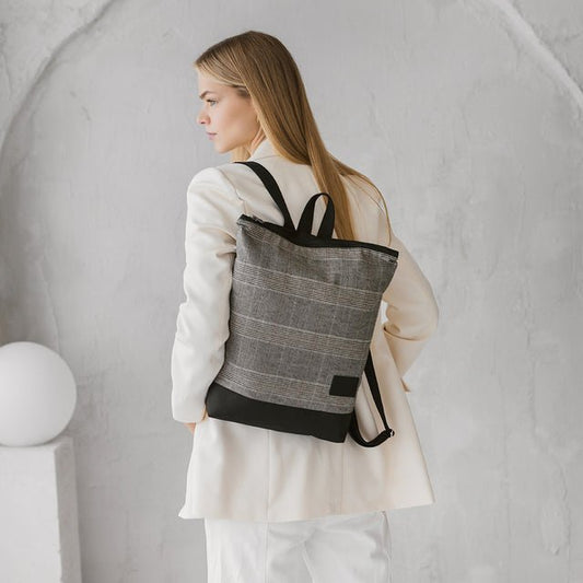 1. Woman wearing MUNI Tartan Backpack in lifestyle setting, showcasing minimalist design