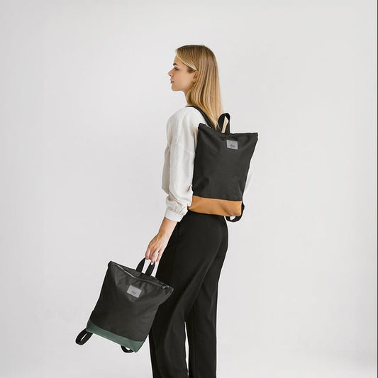 1. Woman holding Muni waterproof backpack with tan leather bottom, showcasing stylish design in lifestyle setting