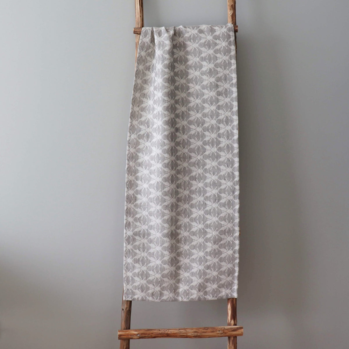 2. Table runner with Hanikatsi fly pattern draped over wooden ladder, highlighting linen-cotton blend texture and design