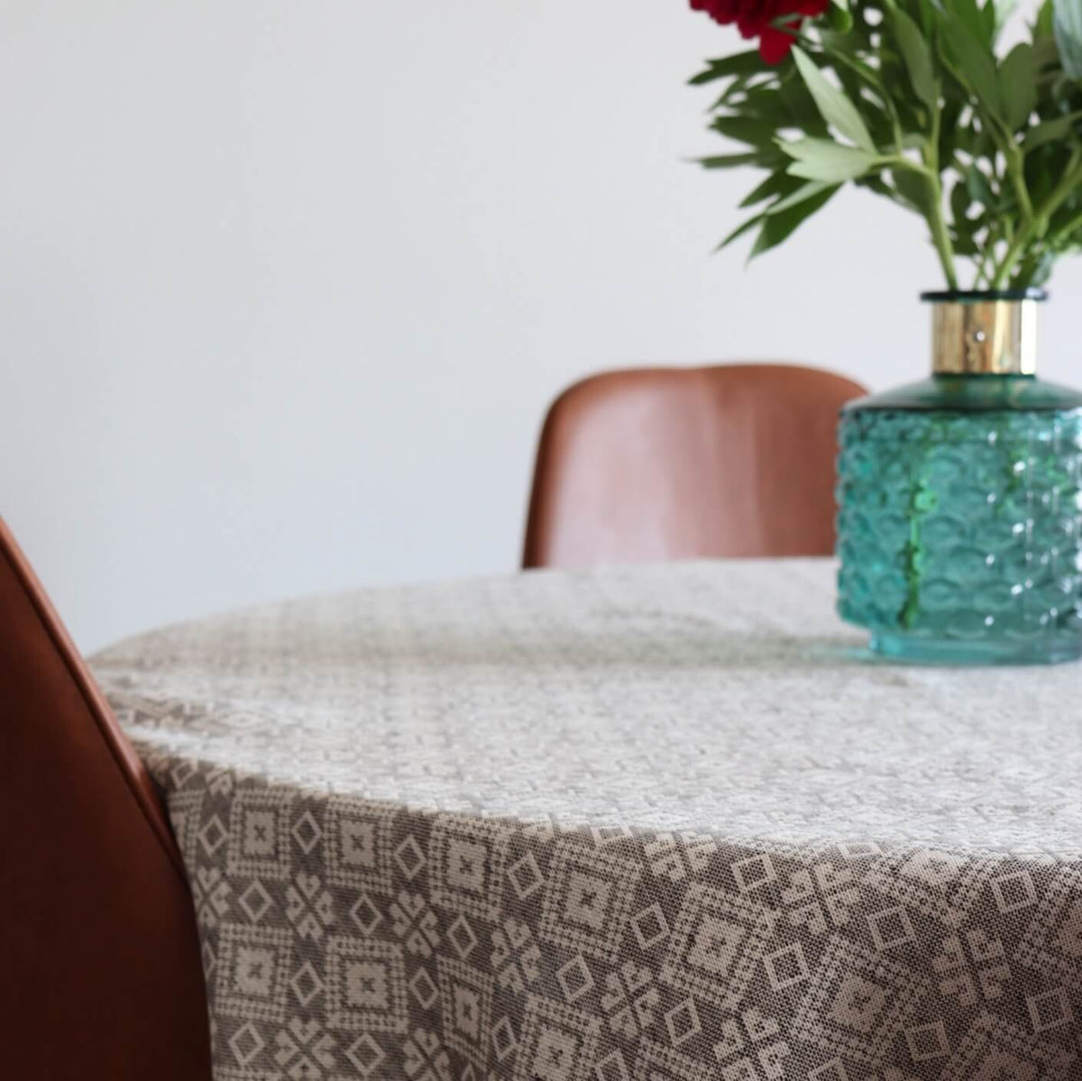 2. Close-up of LOKO Tartumaa tablecloth with Kodavere folk art pattern, showing texture and design, with a blue vase and red flowers partially visible