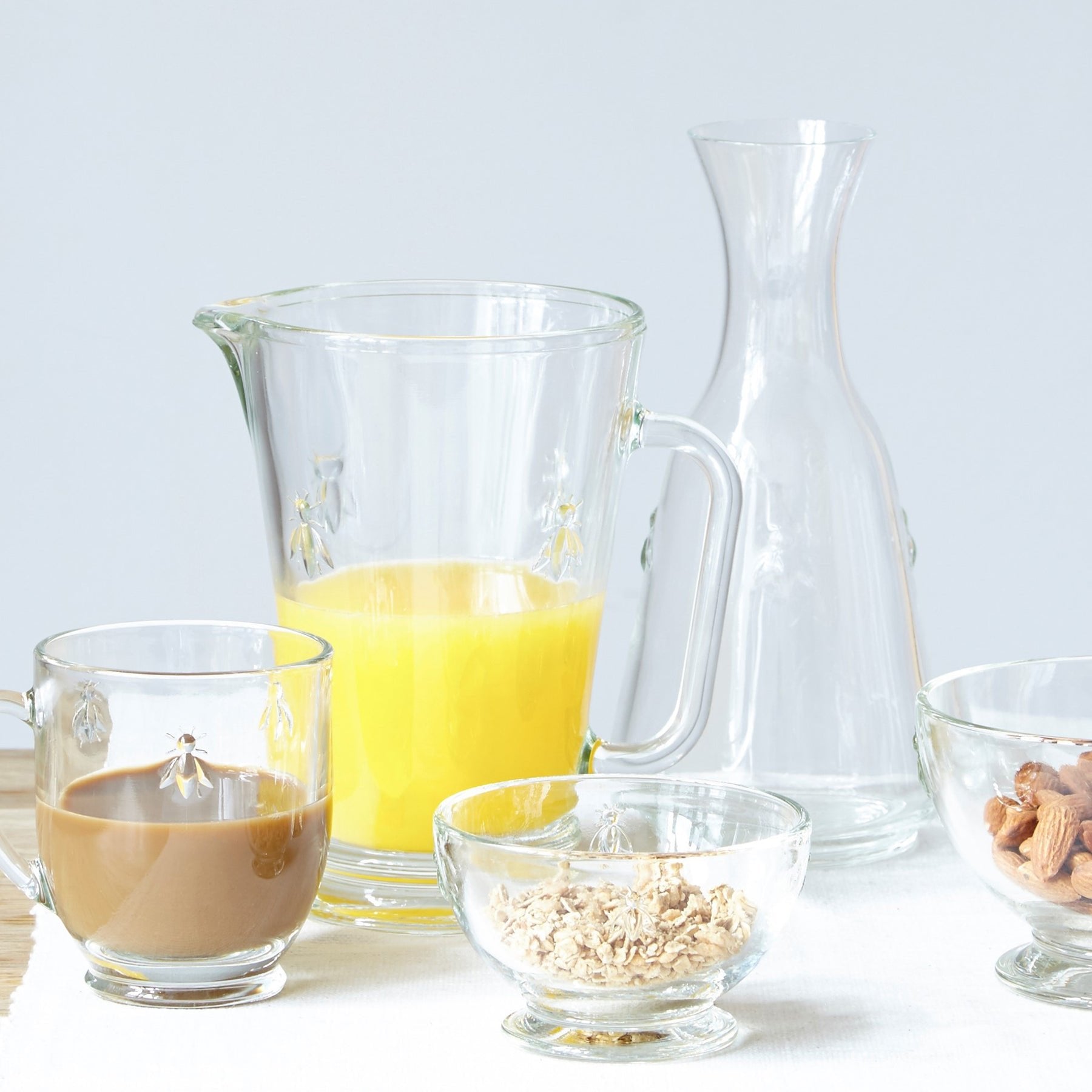 1. La Rochère Bee glass jug filled with orange juice, surrounded by matching glassware on a table setting