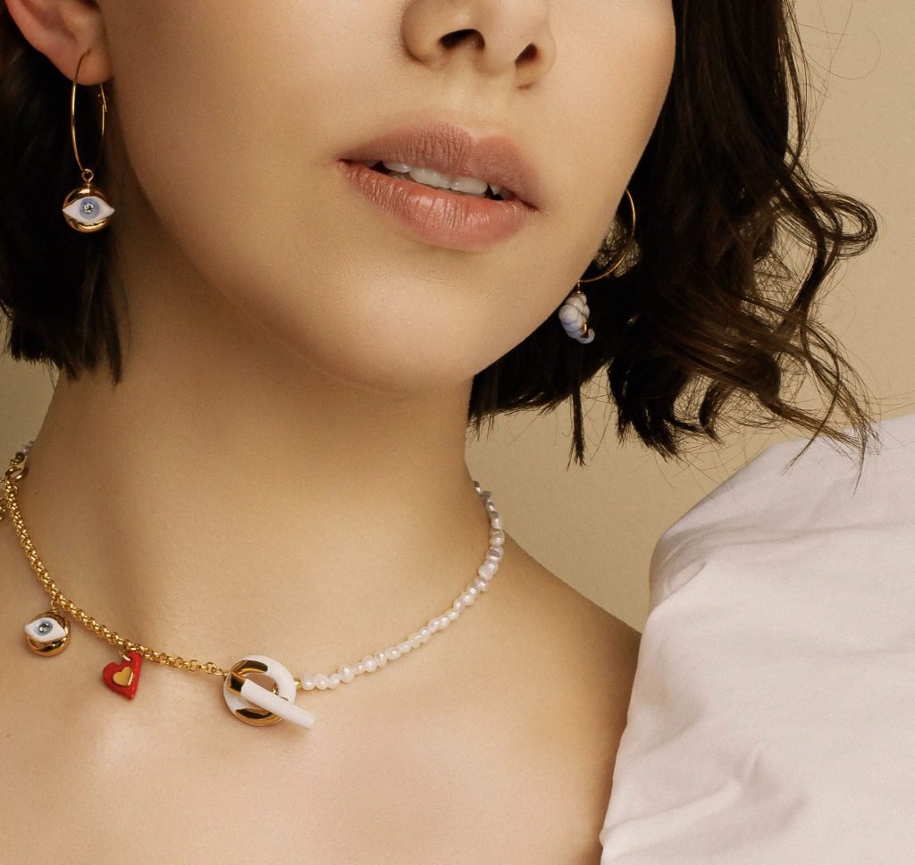 1. Woman wearing SCULP 2 Love And Protect U earrings with Eye of Protection charm and heart pendant, styled with matching necklace