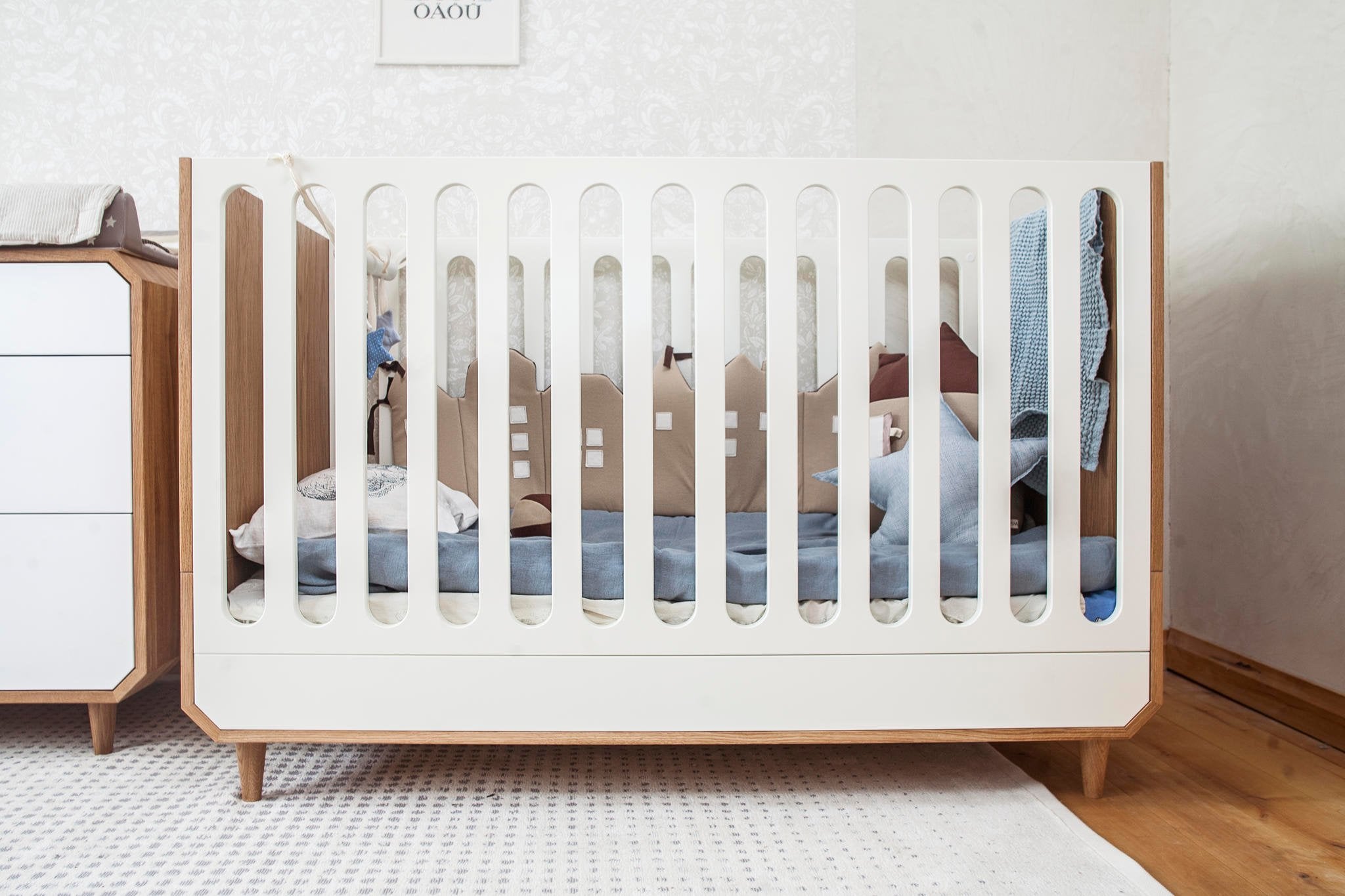 1. Baby crib with blue star-shaped toy hanging, showcasing a cozy nursery setting and enhancing sensory development with crinkle and ring sounds.