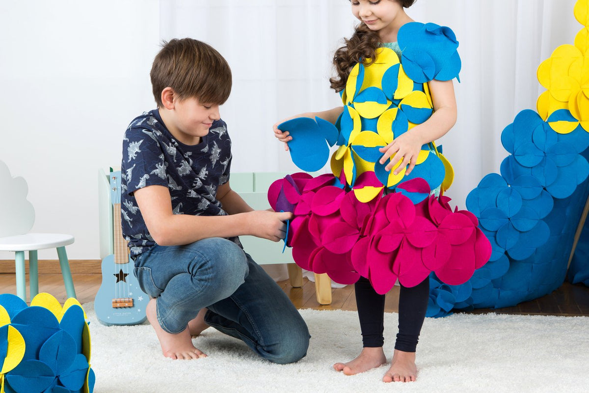 8. Boy assisting girl in assembling a colorful felt costume in a playroom