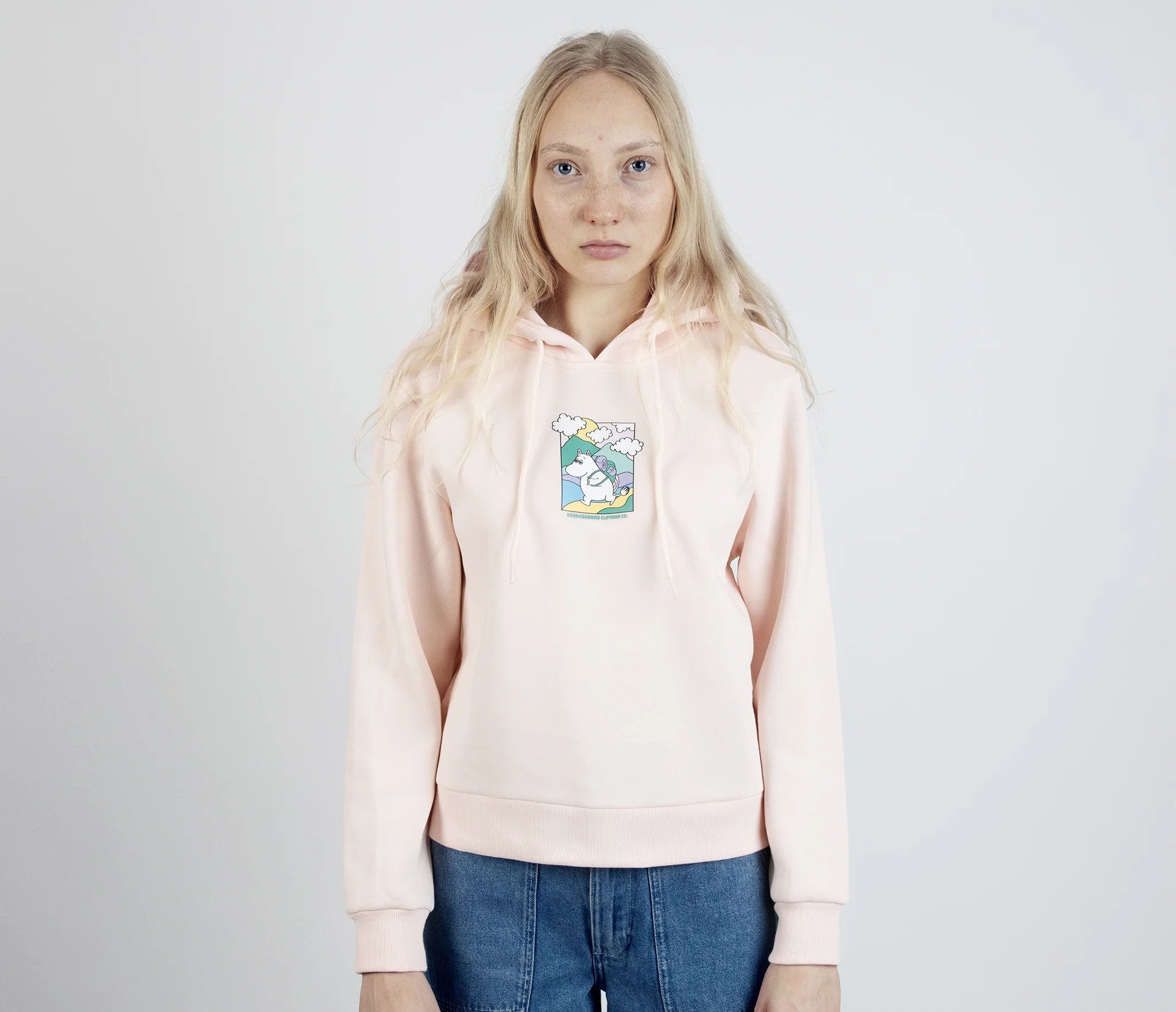 1. Women's light pink Moomintroll's Adventure Hoodie by NordicBuddies, featuring Moomin graphic, worn by female model in studio