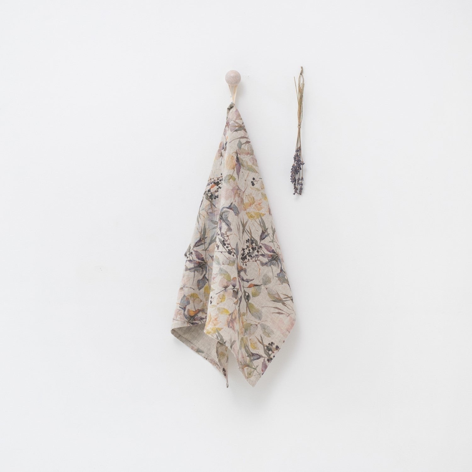 6. Floral print linen kitchen towel hanging on white wall with dried lavender